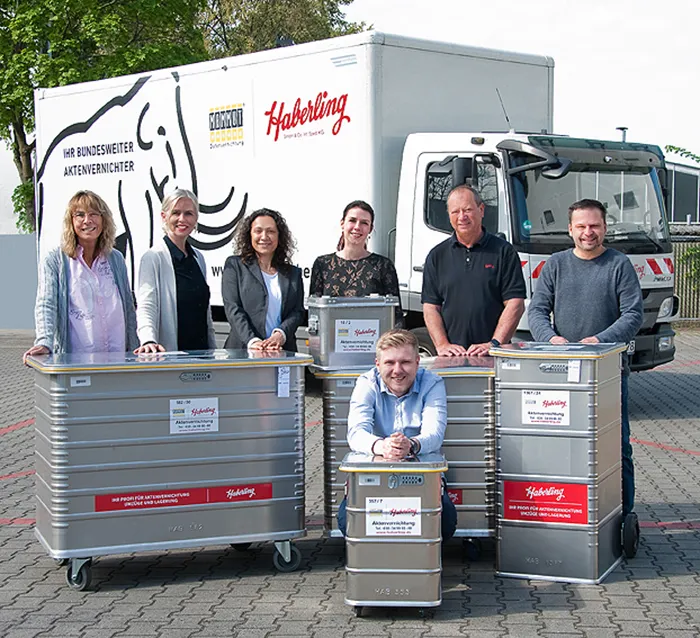 Team der Haberling GmbH vor einem Lkw mit Sicherheitsbehältern für die Aktenvernichtung